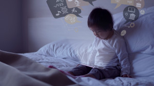 Small toddler sitting on the bed with special effects from ipad