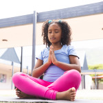 Young girl at school practicing yoga on a mat