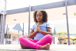 Young girl at school practicing yoga on a mat