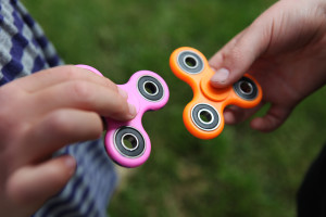 A closeup of two hands holding fidget spinners out toward each other