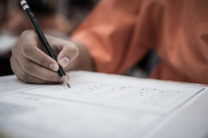 A hand holding a pencil filling out answers on a stardardized test